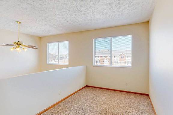 A nook area in the loft with two windows and a ceiling fan.
