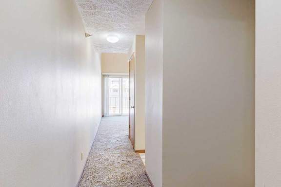 A hallway with an alcove to the hallway bathroom, access to the kitchen, and the living room at the end.