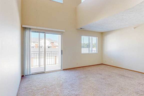 A spacious living room with a sliding glass door and a window.
