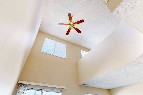 A view of the loft area above from the living room, with two windows and a ceiling fan.