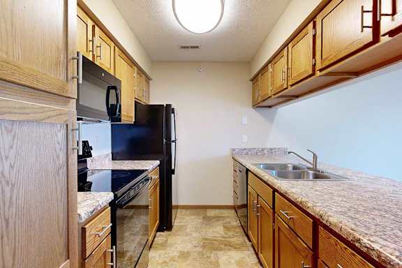 A kitchen with wooden cabinets, black appliances, and granite countertops