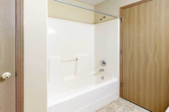 A bathroom with a white tub shower and chrome finishes.