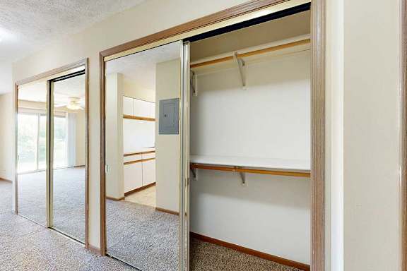 A hall closet with sliding mirror doors, and built-in shelves and hanging space.