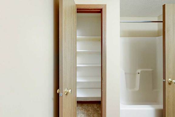 A bathroom with a linen closet, with several built-in shelves.