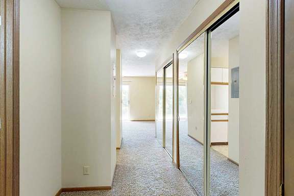 A hallway to the kitchen and living area, with two sliding mirror door closets on the right.
