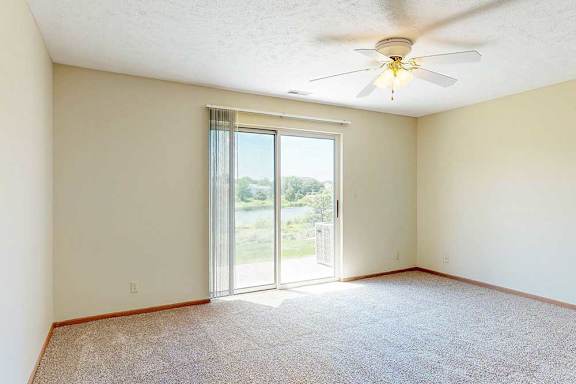 A living area with a ceiling fan and a sliding glass door to a patio, providing plenty of natural light.
