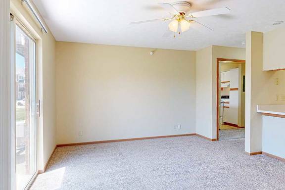 A living area with a ceiling fan and a sliding glass door to a patio, providing plenty of natural light.