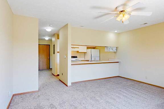 A living area with a ceiling fan and a counter with a passthrough window to the kitchen.