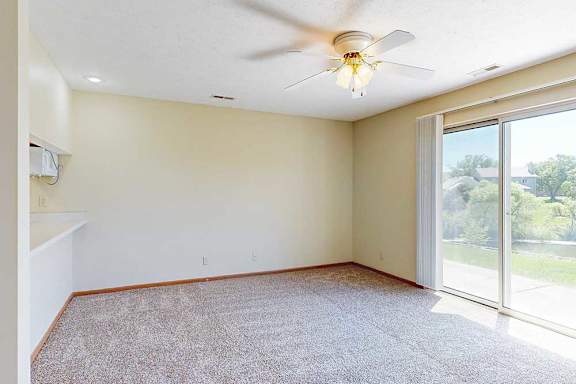 A living area with a ceiling fan and a sliding glass door to a patio, providing plenty of natural light.