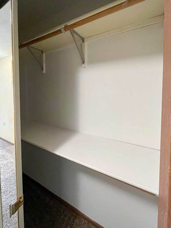 a hallway closet with built-in shelves and hanging rods