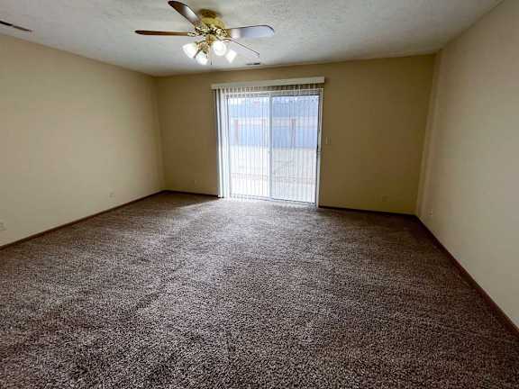 a living room and sleeping area with a ceiling fan and carpeted floor