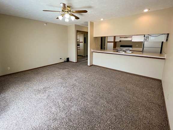 a living room with a ceiling fan and carpeted floor