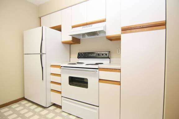 A white kitchen with a refrigerator, oven, and stove.