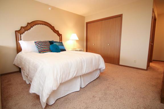 A bed with a white comforter and a pillow with a blue design on it.