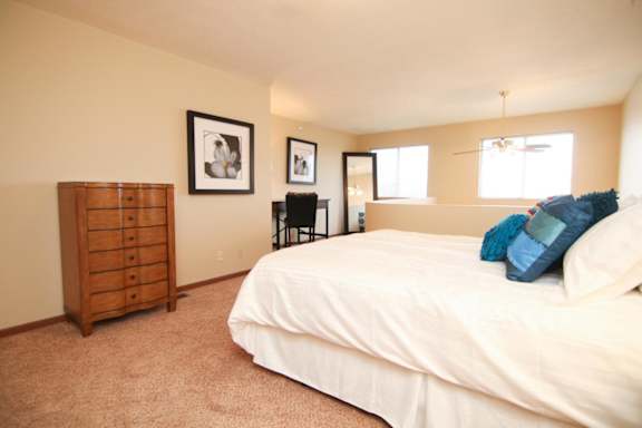 A bedroom with a bed, dresser, and two framed pictures on the wall.