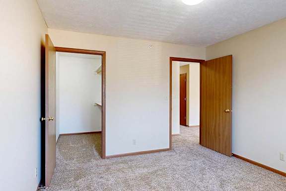 A bedroom with a carpeted floor and a long walk-in closet.