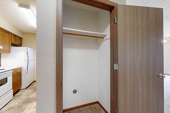 A closet in the hallway with a built-in shelf, next to the kitchen.