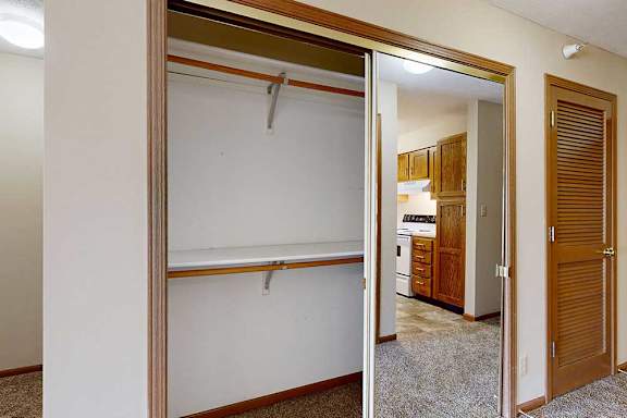 A sliding mirror door closet with two built in shelves in the front hallway next to a mechanical closet.