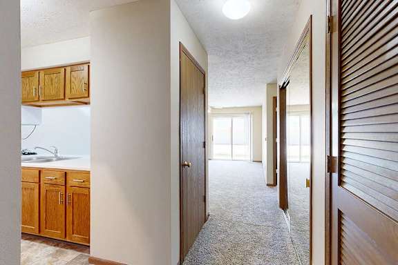 A long hallway with access to the kitchen and a few closets on either side.