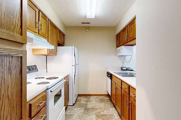 A kitchen with white appliances and wooden cabinets.