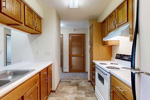 A galley kitchen with wooden cabinets and a white appliances.