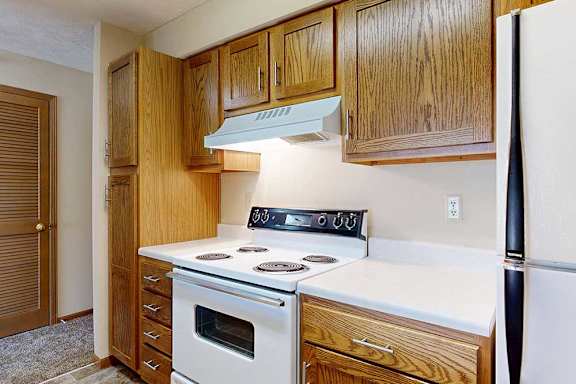 A kitchen with a white appliances, a white countertop, and wooden cabinets.