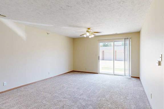 A living room with a ceiling fan and sliding glass door.