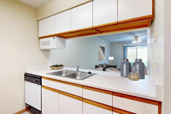 A kitchen with white cabinets and a opening to the living room