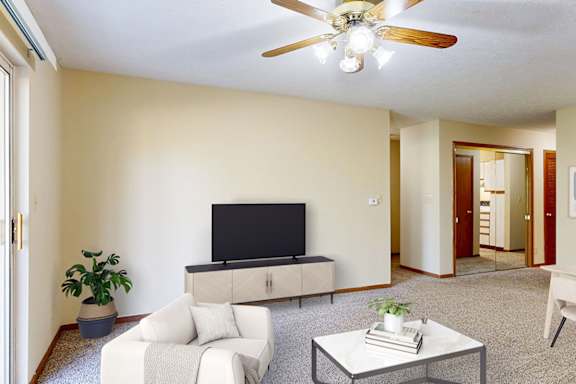 A living room with a television, a white couch, and a coffee table.