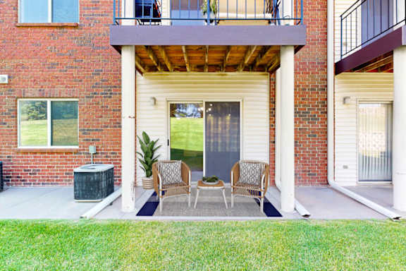 A patio with a table and chairs is surrounded by a brick building.