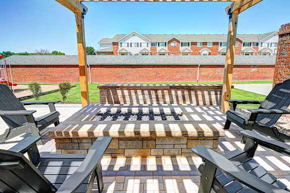 A fire pit is surrounded by black chairs on a patio.