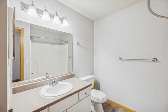 A white bathroom with a sink, toilet, and mirror.