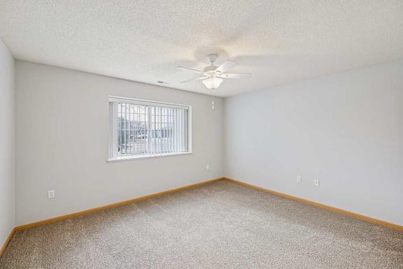A room with a window and a ceiling fan.