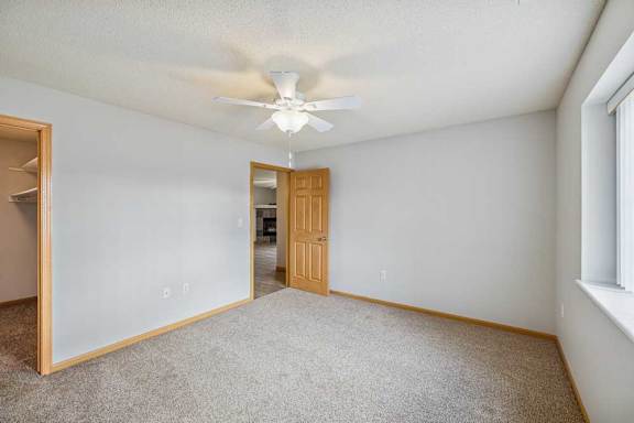 A room with a ceiling fan and carpeted floor.