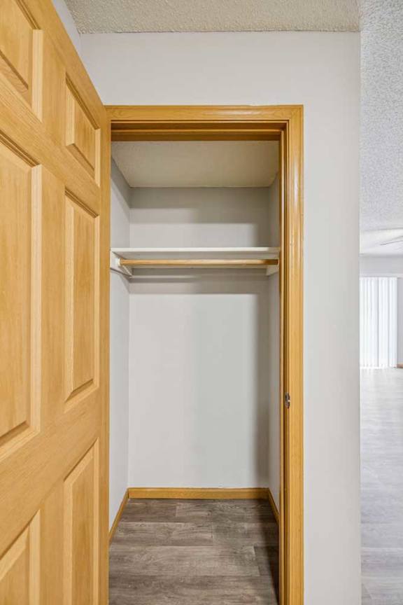 A white hallway with a wooden door and a carpeted floor.