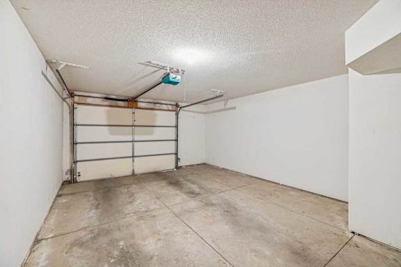 A garage with a white wall and a grey floor.
