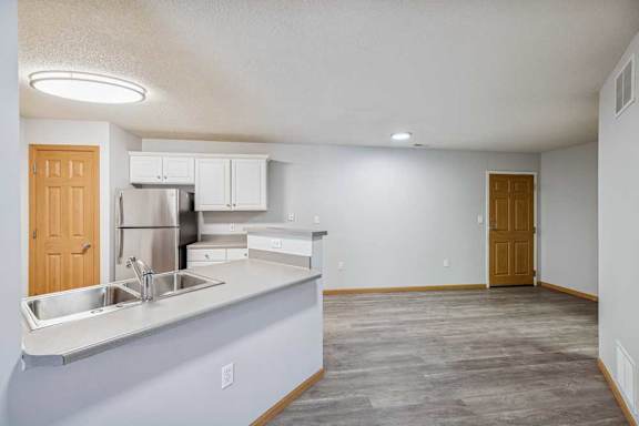A kitchen with a refrigerator, sink, and cabinets.