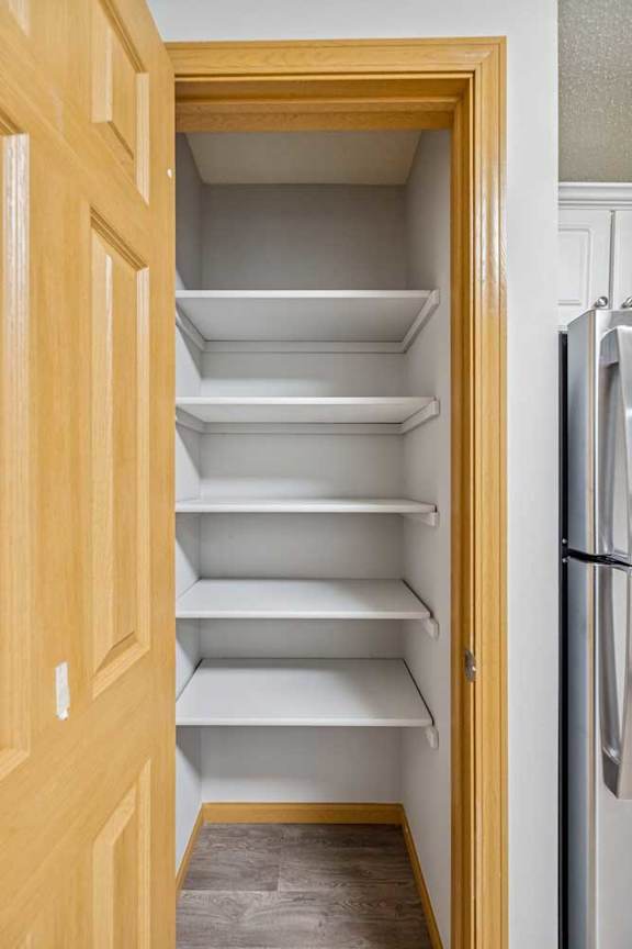Empty white shelves in a wooden pantry.