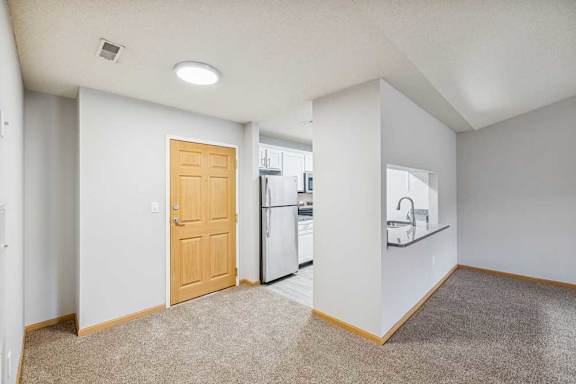 A kitchen area with a refrigerator, sink, and a door.