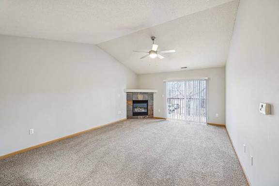 A spacious living room with a fireplace and a ceiling fan.