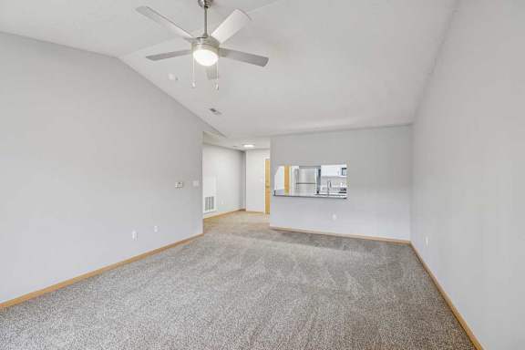 A room with a ceiling fan and carpeted floor.