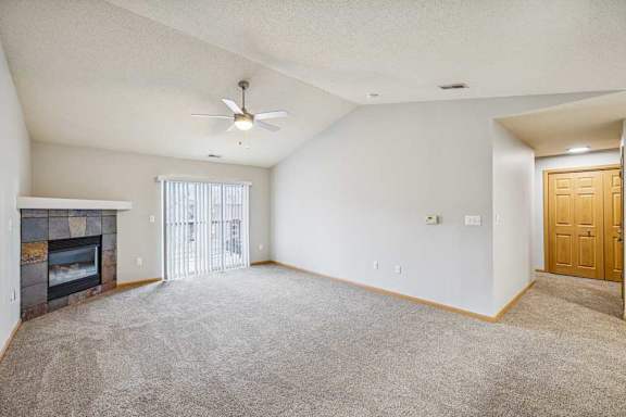 A spacious living room with a fireplace and a ceiling fan.