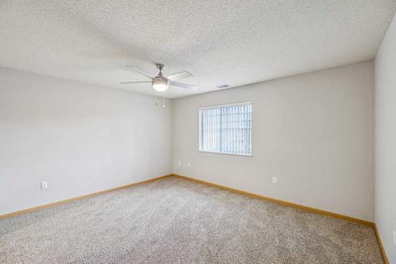 A room with a ceiling fan and a window with blinds.