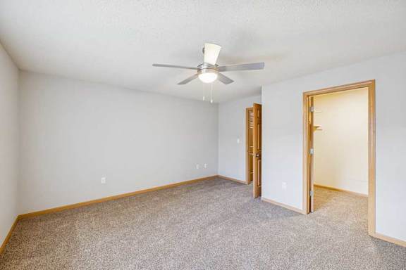 A room with a ceiling fan and carpeted floor.