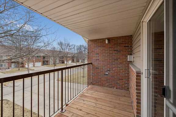 A balcony with a metal railing and a brick wall.