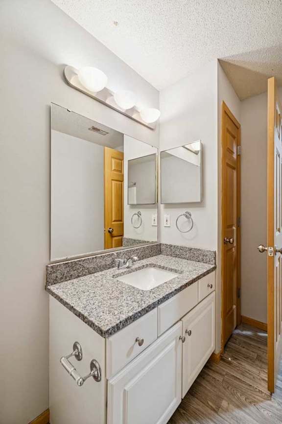 A bathroom with a sink, mirror, and wooden door.