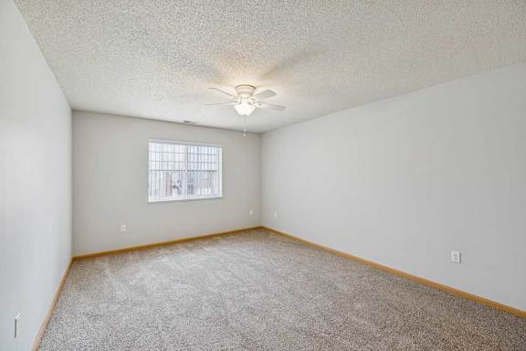 A room with a ceiling fan and carpeted floor.