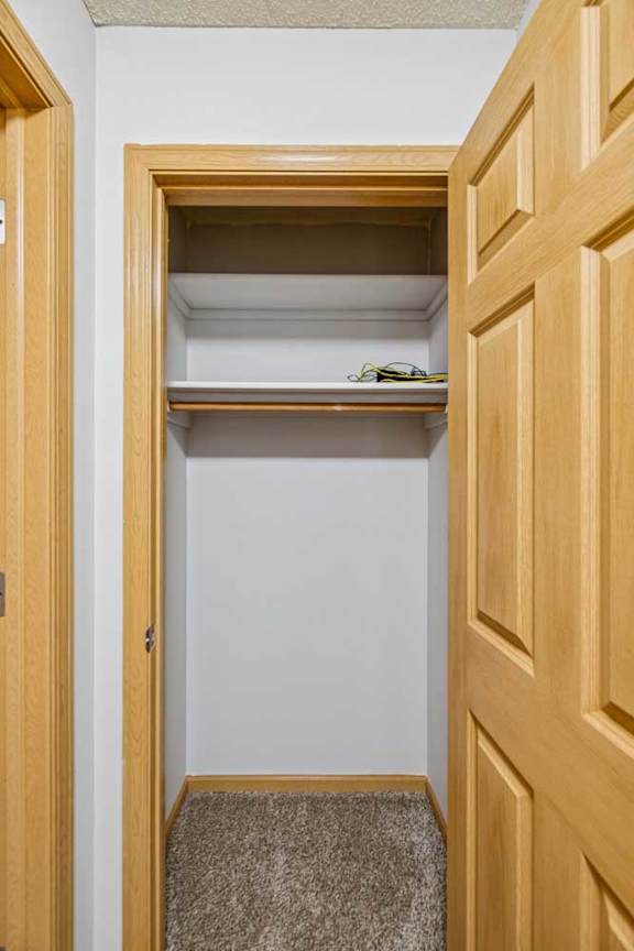 A small closet with a shelf and a pair of glasses on it.