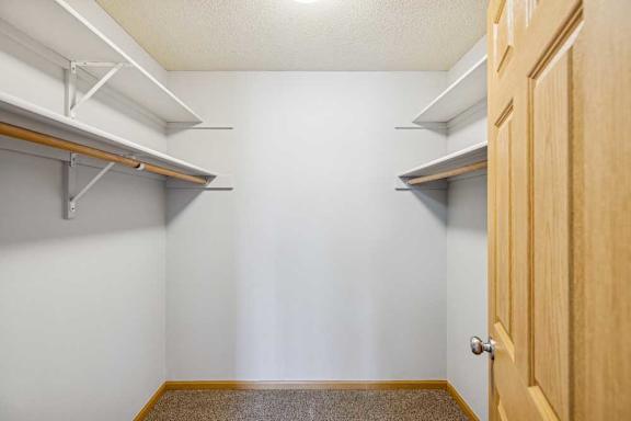 A white wall with a brown carpet and a wooden door.
