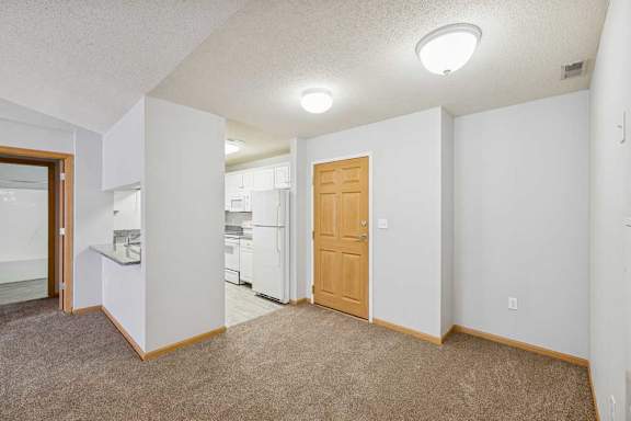 A kitchen area with a refrigerator, sink, and cabinets.